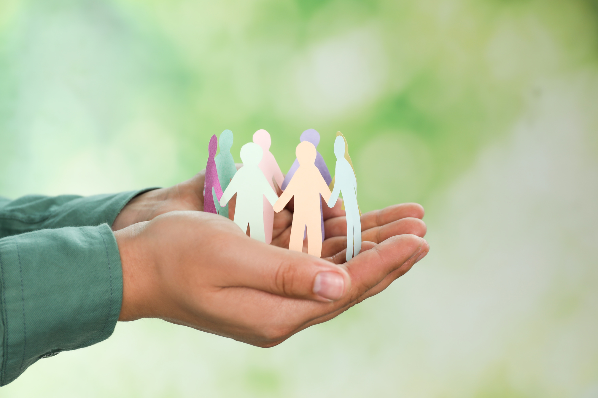 Man Holding Paper Human Figures on Blurred Background, Closeup.